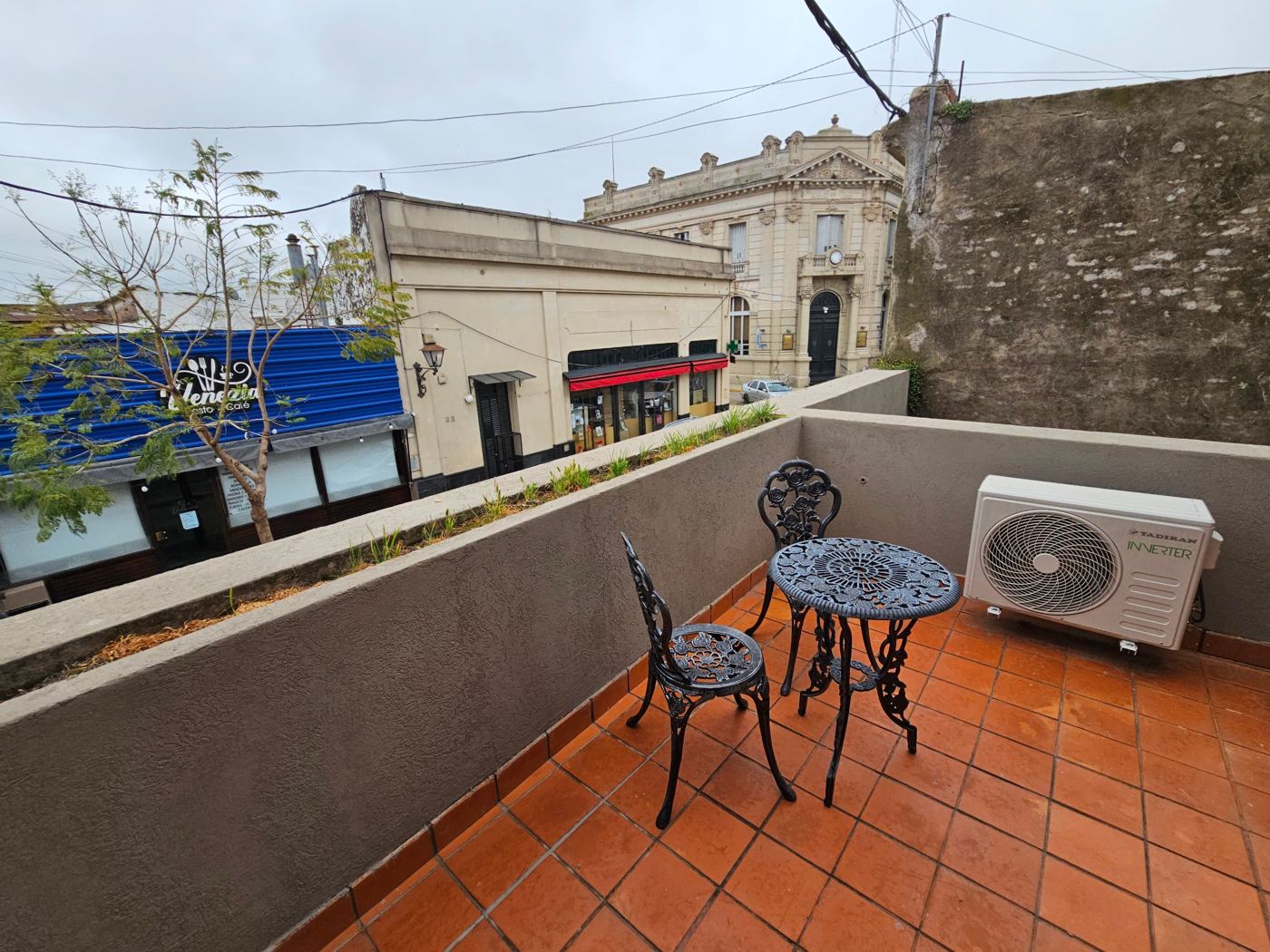 Balcón privado con mesa de hierro y vista a la calle